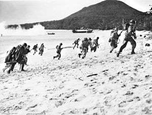 Soldiers running up a beach from the ocean