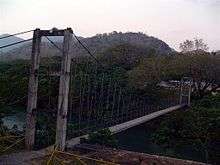 Rustic, gray suspension bridge over a river