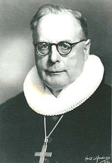 Portrait in black and white of Hans Fuglsang-Damgaard with spectacles and clerical clothing
