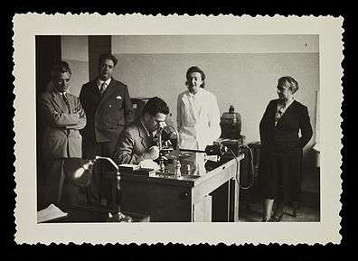 Hans Grüneberg at a microscope surrounded by colleagues in 1952