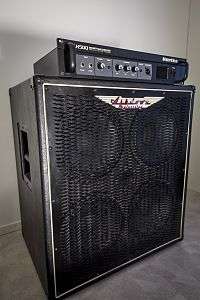 An amplifier unit sitting on top of a bass speaker cabinet. The speaker has four ten-inch loudspeakers.