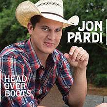 The cover features the artist wearing a plaid shirt and cowboy hat, sitting on a picnic table in a forest park, with his left elbow resting on it.