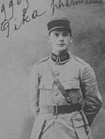 A portrait of a young man dressed in a legionnaire's cap and uniform coat, standing at ease.