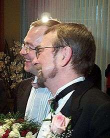 Joyful-looking male couple holding a wedding bouquet