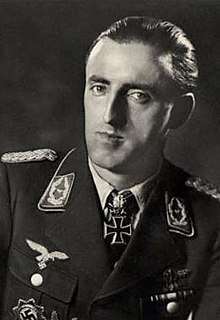 The head and shoulders of a man, shown in semi-profile. He wears a military uniform with various military decorations and an Iron Cross at the front of his shirt collar.