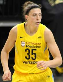 Hip high portrait of young woman with hair up in a bun wearing a yellow basketball uniform number 35
