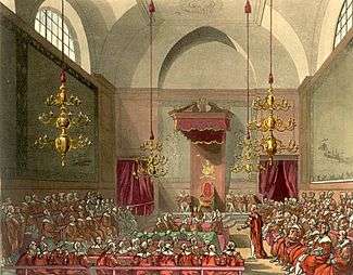 View of the House of Lords from the inside. Their lordships are sitting on three sides of a square, with the Speaker of the House, and the royal throne making up the fourth side.