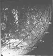 Black and white satellite image of a hurricane with an eye and well organized structure. Due to the storm's position near the edge of the image, most of the hurricane is not visible. The curvature of the Earth is visible on the right, and a coordinate grid with labels has been superimposed on the image.