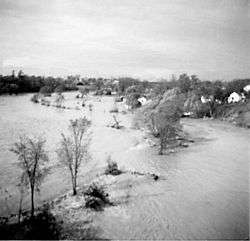 A generally flat area is completely submerged by water; trees are scattered throughout.