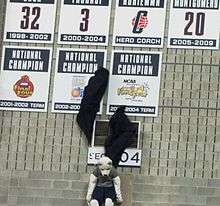 Connecticut Huskies mascot Jonathan pulling down two black curtains, unveiling placards honoring the 2002&ndash;03 and 2003&ndash;04 women's basketball national championship teams