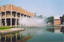 Low modern building, with large pool and fountains in front