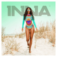 Photograph of Inna posing in a colorful bathing suit while at a beach.