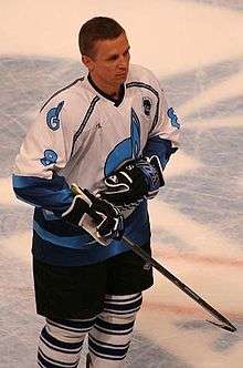 Igor Larionov stands on the ice. He is wearing a blue and white jersey.