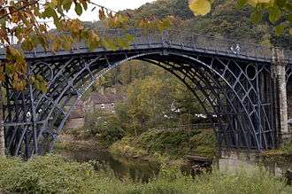 A tall iron bridge stands above a small gorge.