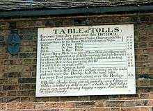 Antique table of bridge tolls now displayed on the outside of the toll house. Tolls range from a halfpenny for a pedestrian to two shillings for a large coach