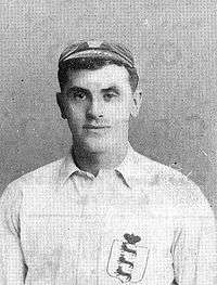 Head and upper torso of a young white man wearing a cap and a white shirt with a badge showing three lions.