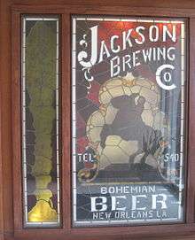 Stained glass panel with the silhouette of a man on a rearing horse and lettering for "Jackson Brewing Co."