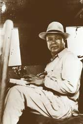 A seated Jaipal Singh, in light suit and hat