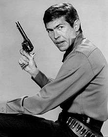 Headshot of a man holding a gun and wearing a gun belt.