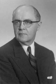 Photographic portrait of Adams, wearing a black suit and spectacles