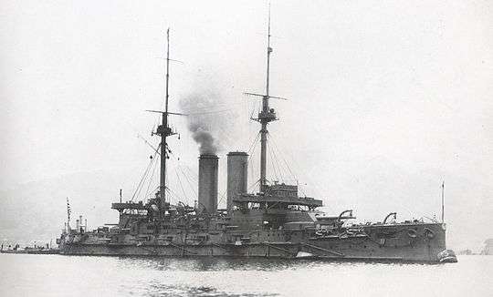 Large warship with smoke rising from the smokestack.