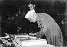 A bespectacled Jawaharlal Nehru bending over a large book