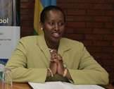 Jeannette Kagame shown sitting at a desk at a public event, wearing a green jacket