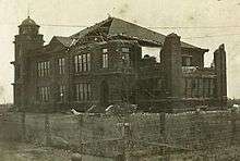 Old photo of a building that has part of its facade damaged.