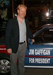 Gaffigan standing next to a car reading "JIM GAFFIGAN / FOR PRESIDENT"