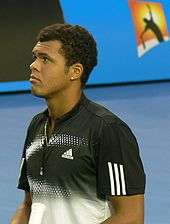 Tsonga in a white shirt lookinh away from the camera.
