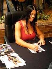 Chyna seated at event desk, signing