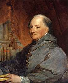 A painting of an elderly, balding, priest wearing a gray robe and a large cross necklace sits, facing left, in front of a brown curtain and bookshelf.