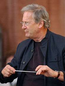conductor John Eliot Gardiner with his baton, facing to the left