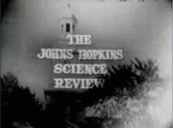 Television screenshot looking up at the bell tower of a building through tall trees. The  words "The Johns Hopkins Science Review" are superposed on the image.