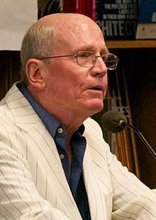 Head and shoulders image of Yardley wearing glasses, white jacket with grey stripes