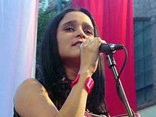 Julieta Venegas, a young woman with dark hair, singing onstage