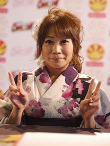 Junko Takeuchi holding two peace signs while smiling
