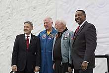 Two men in suits and two in flight jackets pose together