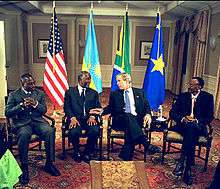Four presidents seated on chairs: Joseph Kabila of the DRC, Thabo Mbeki of South Africa, George W. Bush of the U.S. and Paul Kagame of Rwanda; the four countries' flags are behind them, and Bush appears to be talking