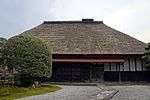 Large wooden house with thatched roof.