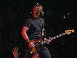 Urban playing a bass guitar onstage