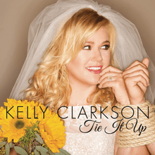 Clarkson in a wedding dress had her left hand tied up to her groom, whom she looks on, smiling, while holding a sunflower bouquet on her right hand. The words "Kelly Clarkson" and "Tie It Up" were written in the lower middle in black letters.