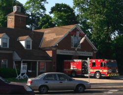 A brick fire house with a fire truck sitting out front