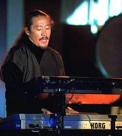 A man in black clothing behind a set of keyboard instruments
