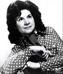 A woman with long dark hair wearing a polka-dot blouse