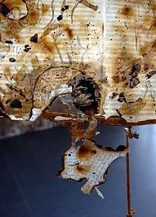 The installation "Les partitions de vent" (detail), 2013. Burned sheet music drawn upon, resin, found object (music stand)