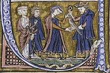 A bearded man wearing a crown gives a falcon to a younger man who is accompanied by a woman and a man.