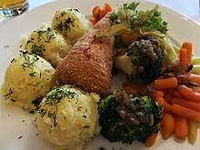 Breaded chicken cutlet served with mashed potatoes, broccoli, carrots, lettuce and garnished with physalis