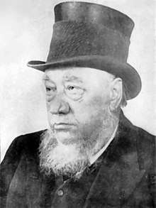 An old man with a grey beard and a black top hat