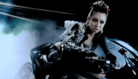 The image features a Japanese woman, sitting on a road motorcycle, in front of a black screen. A clear light is seen from the top-left corner.